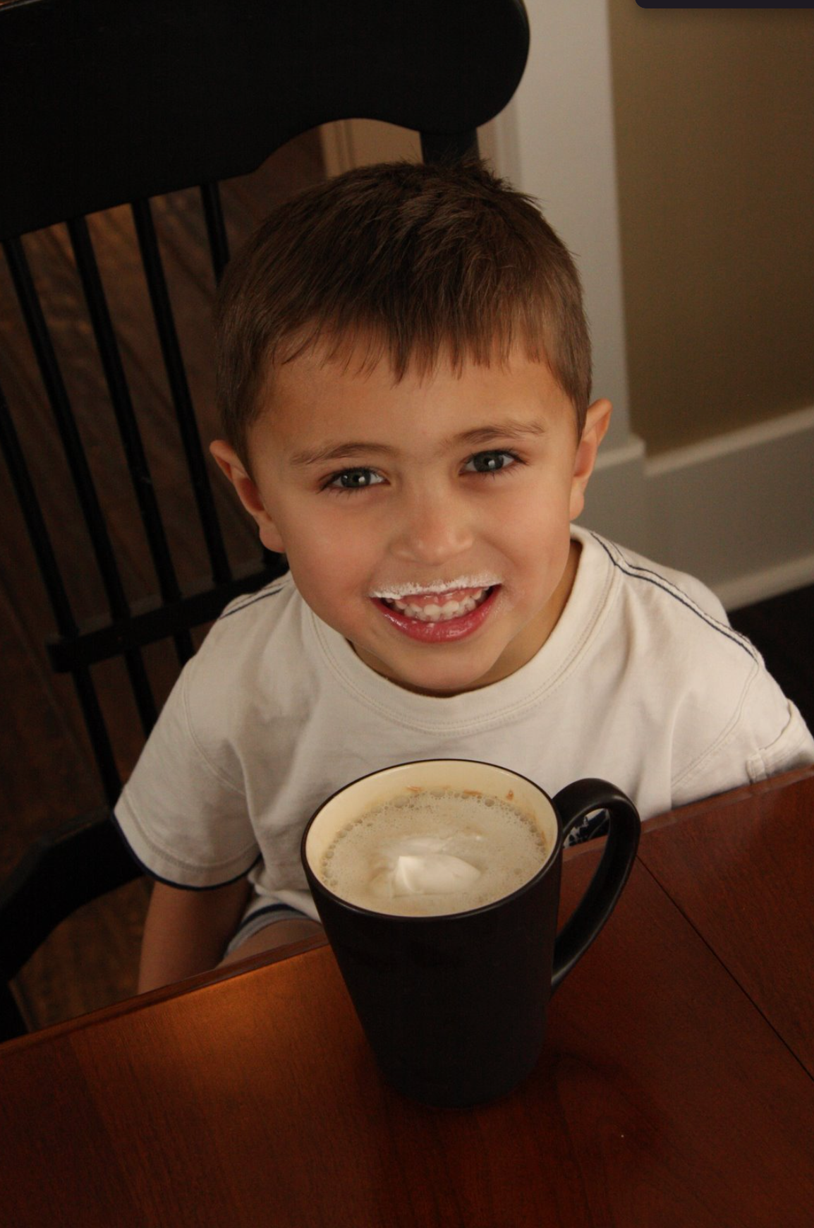 A child enjoying a mug of Grandma D's hot chocolate with a big smile